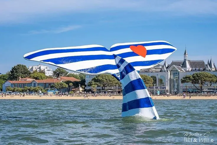 Sculpture de queue de baleine rayée bleu et blanc devant le front de mer d'Arcachon