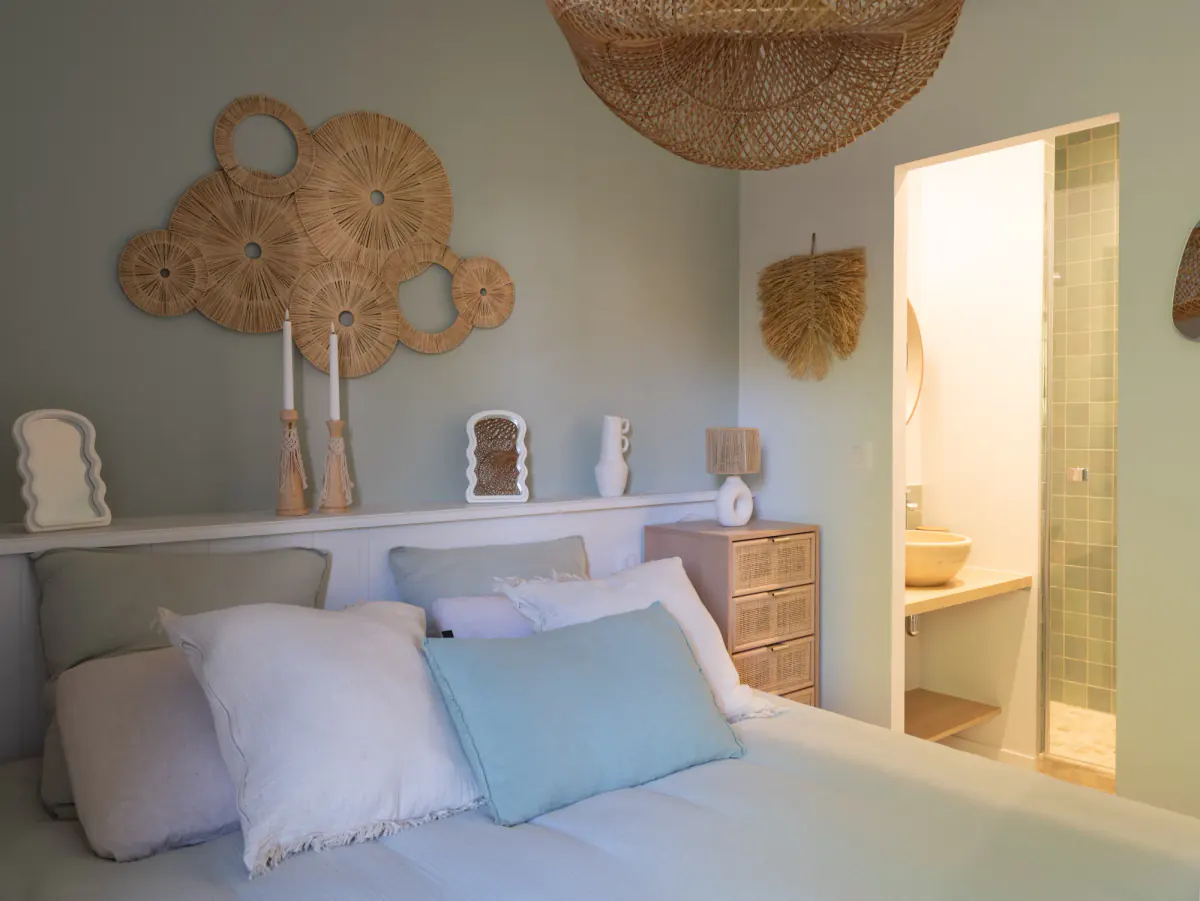 Chambre vert d'eau de Côté Sable : lit double, décor mural en raphia et salle d'eau attenante
