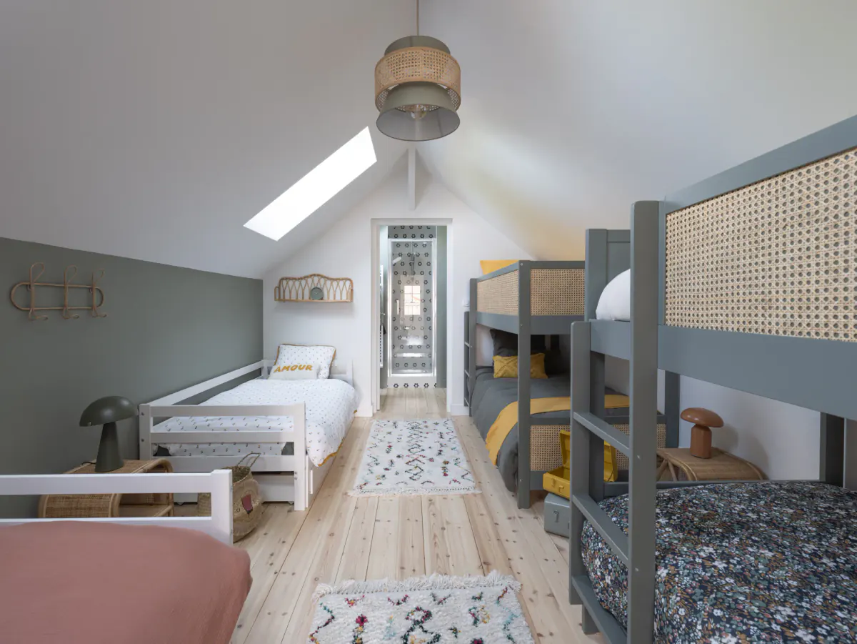 Chambre dortoir de Côté Sable : lits superposés cannés et lits simples sous les combles